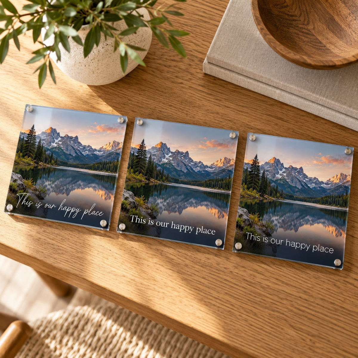 Three acrylic prints of the same mountain lake photo showing the phrase This is our happy place in script, serif, and sans-serif fonts