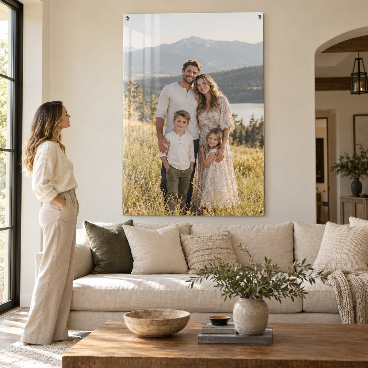 Oversized family photo on clear acrylic hung on a living room wall above a sofa, with a woman standing nearby for scale