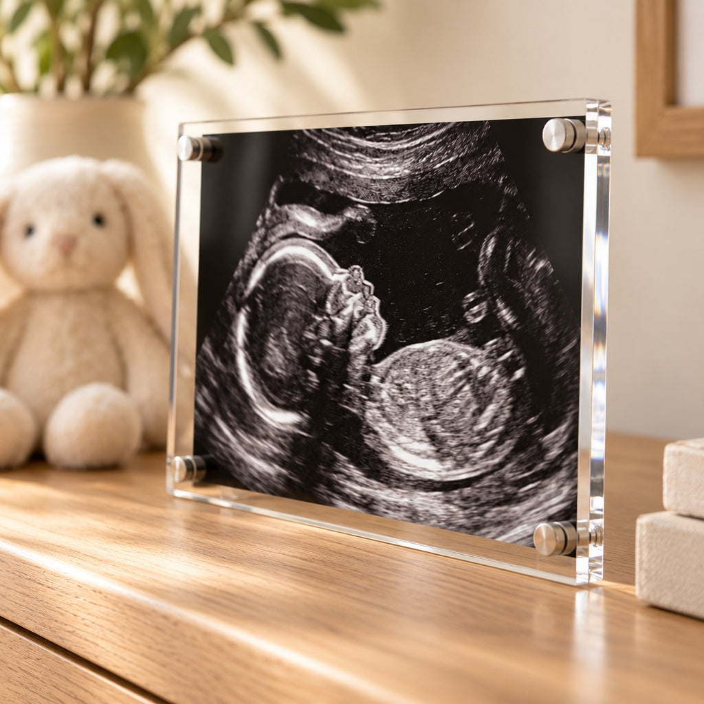 Black and white sonogram acrylic print standing on a wooden shelf in soft window light
